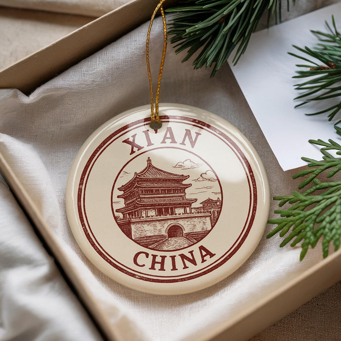 A round ornament with a picture of a Chinese temple and the text "XIAN CHINA" is displayed in a box with pine branches.