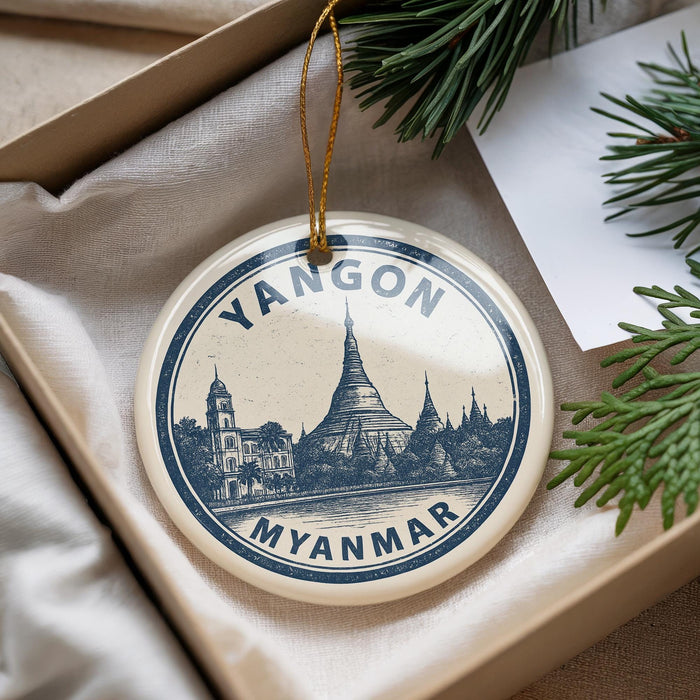 A decorative ornament with a circular design featuring a temple and the text "YANGON MYANMAR" is displayed on a beige surface.