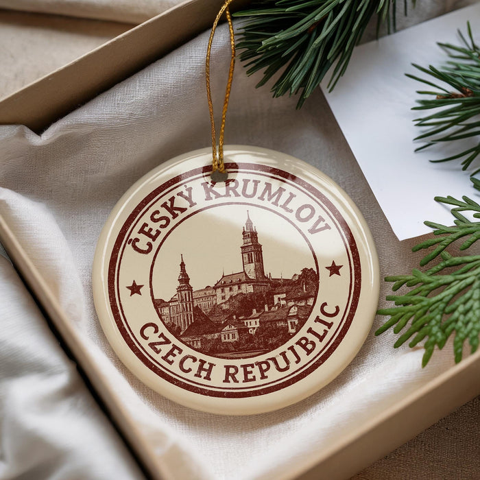 A circular ornament with a picture of a town and the text "CESKY KRUMLOV CZECH REPUBLIC" is displayed in a box with pine branches.