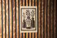 A sign with a black and white illustration of three vases with plants inside, mounted on a wooden wall.