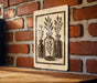 A sign with a black and white illustration of three vases with plants on a brick wall.