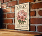 A vintage-style seed packet with a floral illustration is hanging on a brick wall.