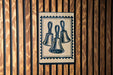 A sign with three bell-shaped illustrations is displayed on a wooden wall.