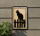 a black cat sitting on a wooden fence.