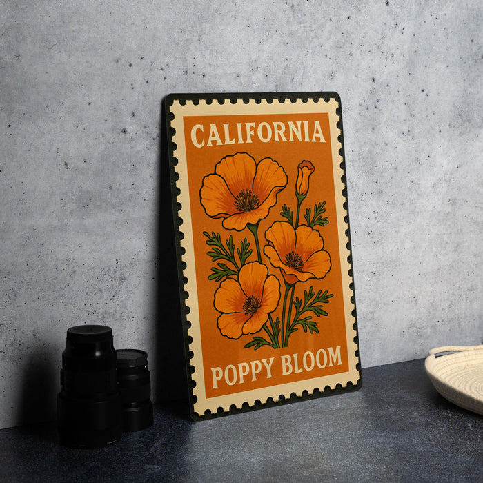 A framed poster of a poppy flower with the text "California Poppy Bloom" is displayed on a table, accompanied by a stack of black camera lenses and a white dish.