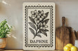 a decorative sign with a floral design, placed on a shelf next to a wooden cutting board and some potted plants.