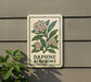 a sign with a floral design and the text "DAPHNE BLOSSOMS" on it, mounted on a wall next to a plant.