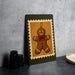 A framed image of a gingerbread man is displayed on a wall, with a stack of black cups and a white dish visible to the side.