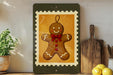A framed image of a gingerbread man is displayed on a shelf, surrounded by kitchen utensils and a potted plant.