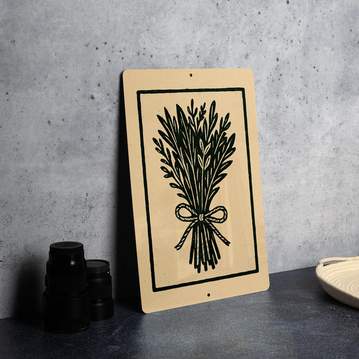 a beige sign with a black illustration of a bunch of leaves and a bow on it, placed on a gray countertop next to a stack of black camera lenses.