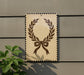 a decorative wreath-like design on a wall, with a plant to the left of the frame.