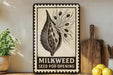 a seed pod opening sign with a decorative border, placed on a wooden surface next to a wooden cutting board and some potted plants.