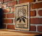 A wooden table with a brick wall in the background, and a framed sign featuring a floral design hanging on the wall.
