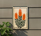 a decorative sign with a floral design, hanging on a wall next to a plant.