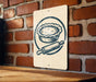 A sign featuring a pie and a rolling pin is mounted on a brick wall.