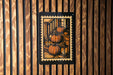 A framed illustration of three pumpkins is displayed on a wooden wall.