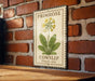 A metal sign with a vintage-style illustration of a yellow flower and green leaves, mounted on a brick wall.