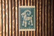 A wooden wall with a green and white sign featuring a stylized goat design.