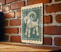 A green and white sign featuring a stylized illustration of a goat is mounted on a brick wall.
