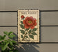 a decorative sign with a large, vibrant red peony flower and green leaves, mounted on a wall.
