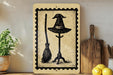 a witch's hat and a broomstick on a shelf, with a wooden cutting board and lemons nearby.
