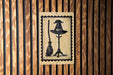 A black and white illustration of a witch's hat and broom is displayed on a wooden wall.