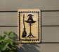 a sign with a witch's hat and broom on a post, mounted on a wall.