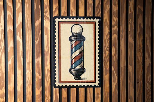 A framed image of a barber pole is displayed on a wooden wall.