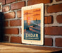 A vintage-style poster of Zador, a coastal town in Spain, depicting a sunset over the sea with silhouetted figures sitting on a pier.