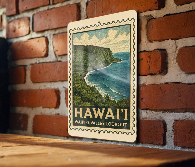 A framed illustration of the Waipio Valley overlooking the ocean, with the text "HAWAII'I WAIPIO VALLEY LOOKOUT" printed on it, is displayed on a brick wall.