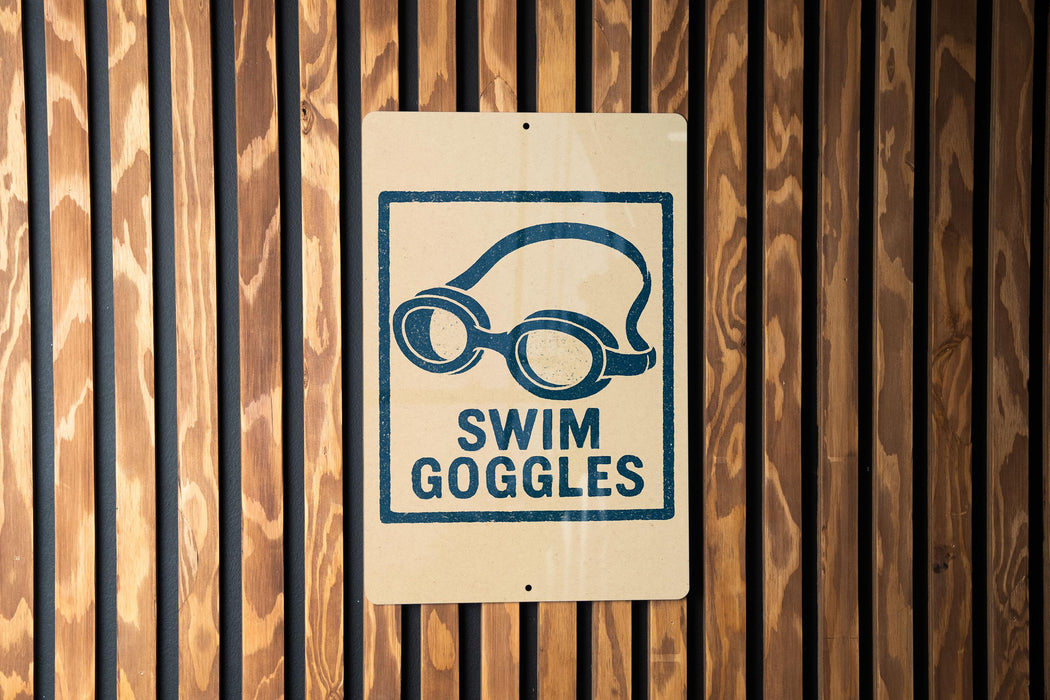 A sign with a blue swim goggles icon is mounted on a wooden wall.
