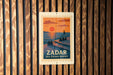 A vintage-style poster of Zador Sea Organ Sunset is displayed on a wooden wall.