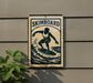 A sign that reads "SKIMBOARD" is attached to a wall, featuring a silhouette of a surfer riding a wave.