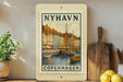 A framed vintage postage stamp depicting a colorful scene of a harbor in Copenhagen, Denmark.