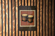 A framed image of two conga drums is displayed on a wooden wall.