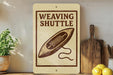 a sign that reads "Weaving Shuttle" with a drawing of a shuttle on it, placed on a shelf next to a wooden cutting board and a potted plant.