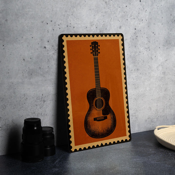a framed picture of an acoustic guitar on a wall, with a stack of black camera lenses and a white dish placed next to it.