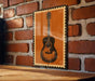 a wooden table with a framed picture of a guitar hanging on the wall next to it.