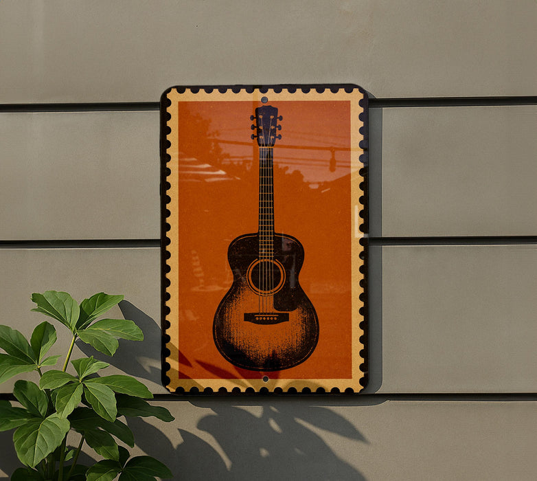 a guitar-shaped sign with an orange background and a black border, mounted on a gray wall.