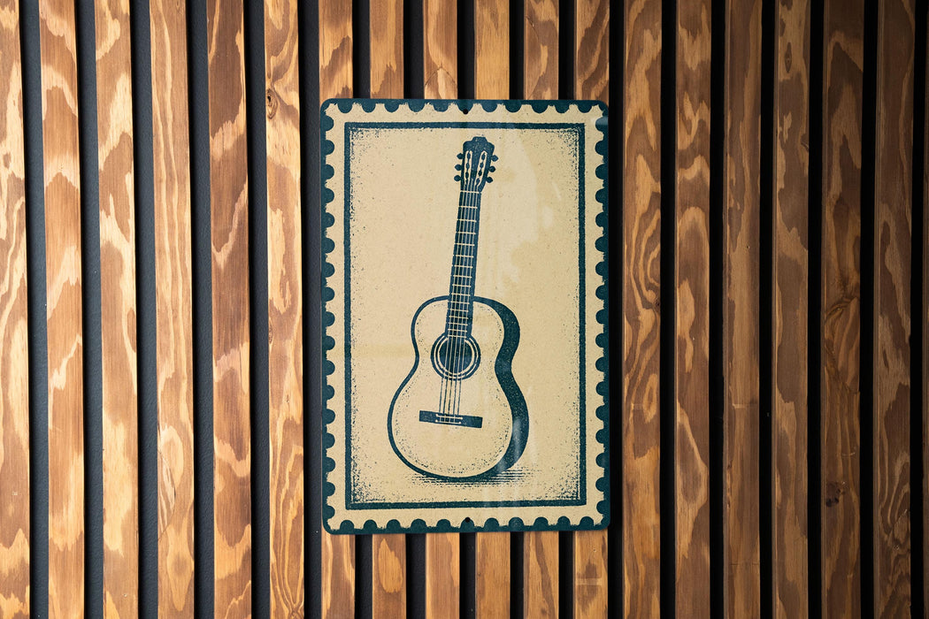 A framed image of a guitar is displayed on a wooden wall.
