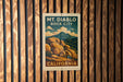 A vintage-style poster of Mount Diablo, a famous landmark in California, is displayed on a wooden wall.