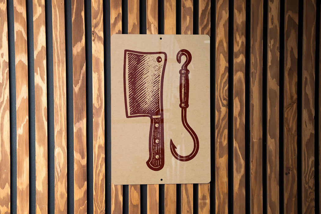 a sign with a picture of a butcher knife and a fishing hook on it, mounted on a wooden wall.
