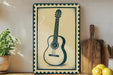 a framed picture of a guitar on a shelf, with a potted plant to the left and a wooden cutting board to the right.