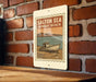 A sign for Salton Sea, Bombay Beach, featuring a vintage-style illustration of a boat on a beach.