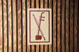 a sign with a red and white design, depicting a musical instrument, such as a violin or cello, against a wooden background.