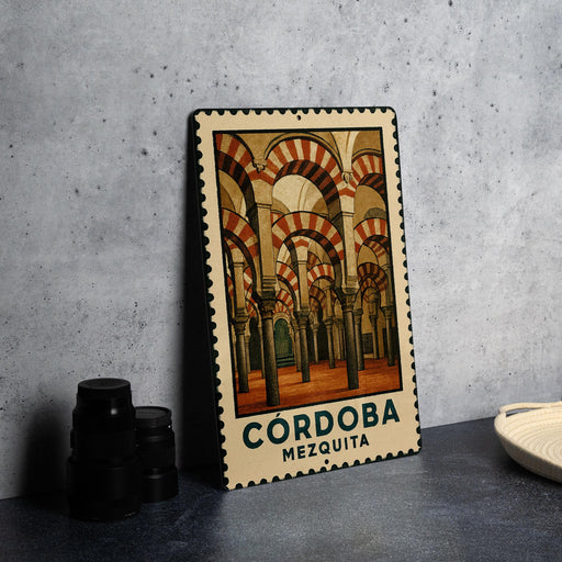 A metal stamp with a picture of the Córdoba Mosque in Spain, featuring arched doorways and columns.