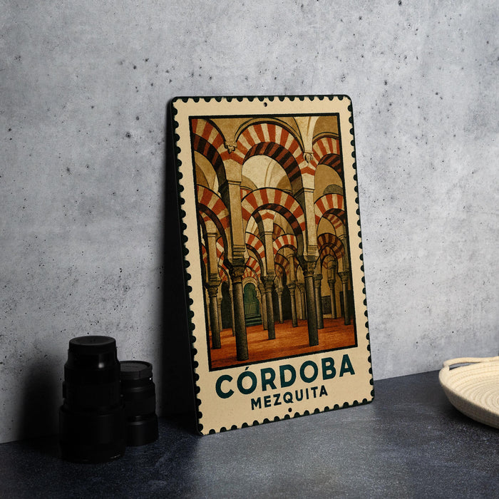 A metal stamp with a picture of the Córdoba Mosque in Spain, featuring arched doorways and columns.