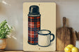A vintage-style illustration of a thermos and a mug is displayed on a wall, accompanied by a wooden cutting board and a potted plant.