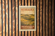 A metal sign with the text "NEBRASKA SANDHILLS COUNTRY" is displayed on a wooden wall.