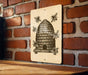A sign featuring a bee hive illustration is mounted on a brick wall.